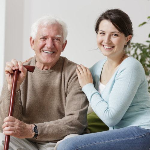 Smiling old man holding a cane and smiling young woman